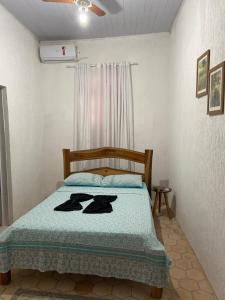 a bedroom with a bed with two black robes on it at Pousada Caminhos da Chapada in Palmeiras +27 photos