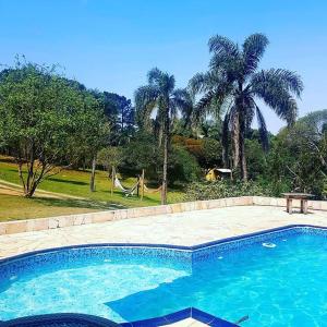 a large swimming pool in a yard with palm trees at Pousada Sitio da Terra e Arte in São Roque