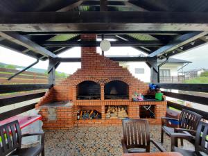 einen Backsteinofen auf einer Terrasse mit Stühlen in der Unterkunft Sat de Vacanta Martisorul Cacica in Suceava