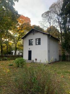 una casa blanca con techo negro en un patio en Ojcówek, en Grodzisk Mazowiecki