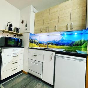 uma cozinha com armários brancos e um micro-ondas em L'AnsloBoys Montagne H2 em Les Deux Alpes