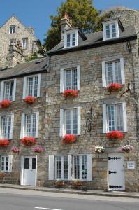 a stone building with white windows and red flowers at Domfront - Numero CINQ in Domfront