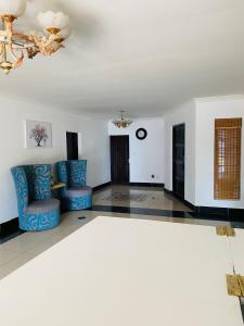 a living room with blue chairs and a chandelier at Airport Doozy Guest House in Kempton Park