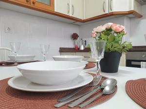 een tafel met een witte kom en borden en bestek bij Arrantzale Beach in Bermeo