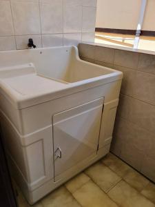 lavabo blanco en un baño con ventana en Residencial Niágara, en Arroio do Sal