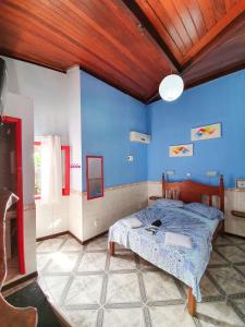 a bedroom with a bed and a blue wall at Papagaio Hostel & Pousada in Morro de São Paulo