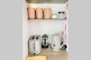 a small kitchen with appliances on a shelf at The Yellow Door Whitstable - Peaceful retreat close to beach in Whitstable