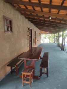 a wooden table and benches sitting under a building at Fazenda Rosmaninho in Alto Paraíso de Goiás +56 photos