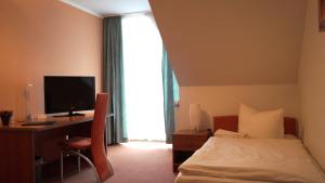 a hotel room with a bed and a desk with a computer at Síu Hotel Magdeburg in Magdeburg