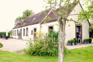 a woman standing in the window of a white building at La PASTORALE in La Puisaye