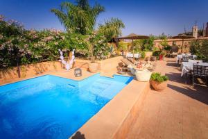 a swimming pool in a resort with people sitting around it at Riad Hizad in Marrakesh