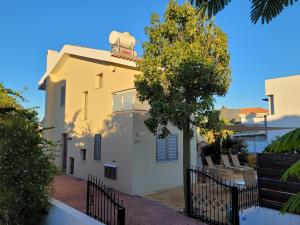 a yellow house with a tree in front of it at Poros 2 Villa in Protaras