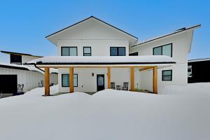 a white house with snow in front of it at Sunlight cottage in Steamboat Springs