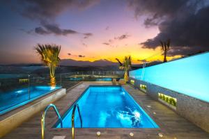 a swimming pool with a sunset in the background at Oleas Suites in Voútai
