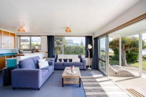 a living room with blue couches and a table at Absolute Beachfront - Waimarama Holiday Home in Waimarama