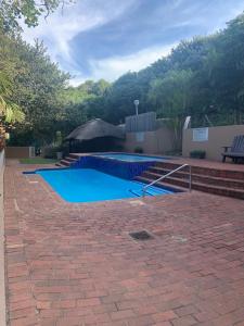 a swimming pool in a yard with a brick patio at Escape to our Happy Place on Umdloti Beach in Umdloti