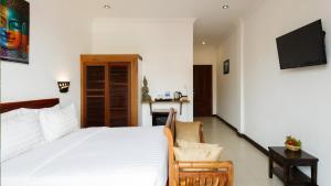 a bedroom with a large white bed and a chair at La Villa du Bonheur in Siem Reap