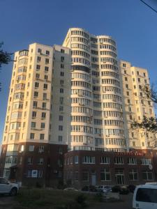 un gran edificio blanco con coches estacionados frente a él en Квартира с видом на море en Chornomorsk