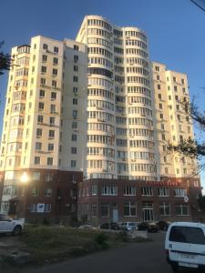 a large white building with cars parked in a parking lot at Квартира с видом на море in Chornomorsk +15 photos