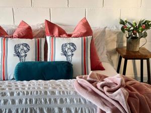 - un lit avec des oreillers rouges et blancs dans l'établissement Barn Cottage Granite Belt Tiny Town Stay, à Wallangarra
