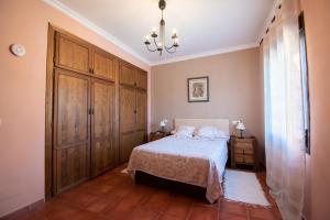 a bedroom with a bed and wooden cabinets and a chandelier at VILLA ELISABETH Piscina y Terraza con Aire Acondicionado in Arriate +25 photos