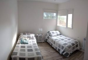 Habitación blanca con 2 camas y 2 ventanas en Balcón del Bosque, en Monte Hermoso