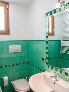 Baño de azulejos verdes con aseo y lavamanos en B&B La Spiaggetta, en Santa Maria al Bagno