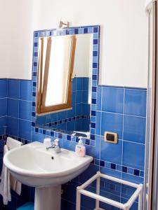 uma casa de banho em azulejos azuis com um lavatório e um espelho em B&B La Spiaggetta em Santa Maria al Bagno
