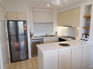 a kitchen with white cabinets and a stainless steel refrigerator at Cypress Lakes Villa Domenica in Pokolbin