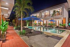 a swimming pool with blue umbrellas and a house at Sahadewa Suites Residence in Kerobokan +15 photos