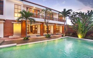 a swimming pool in front of a house at Sahadewa Suites Residence in Kerobokan