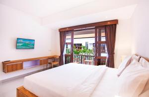 ein Schlafzimmer mit einem weißen Bett und einem Fenster in der Unterkunft Sahadewa Suites Residence in Kerobokan