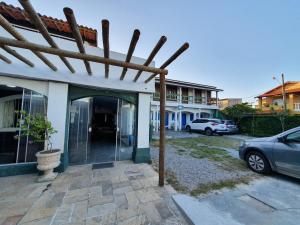 a building with a car parked in a parking lot at Pousada Recanto Verdes Mares in Arraial do Cabo