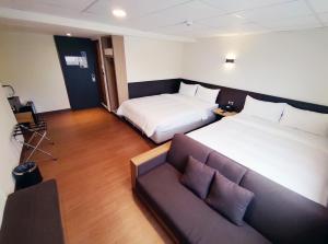 a hotel room with two beds and a couch at 富裕商旅 RICH-hotel in Taitung City