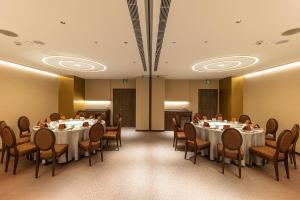 Hotel Metropolitan Premier Taipei في تايبيه: قاعة اجتماعات مع طاولات وكراسي في غرفة