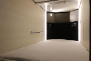 a room with a black door and a white bed at Cabin & Capsule Hotel J-SHIP Osaka Namba in Osaka