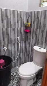 a bathroom with a white toilet and a black bucket at Zeah's Beach Place in Bulusan