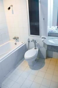a bathroom with a toilet and a tub and a sink at Sweet Home Hotel Betong in Betong