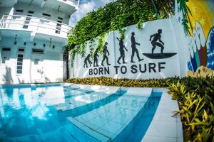 a sign that reads born to surf next to a swimming pool at The Surfer Sri Lanka - Surf Camp in Weligama