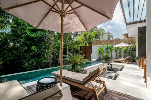 an outdoor patio with an umbrella and a swimming pool at Villa Oiseau Paradis in Ubud