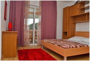a bedroom with a bed and a window with purple curtains at Apartments Luciano in Seget Vranjica