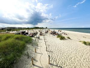una spiaggia con sedie e persone sedute sulla sabbia di Derzeit beliebt - Phänomenaler Ausblick auf Binnen- und Ostsee a Heiligenhafen