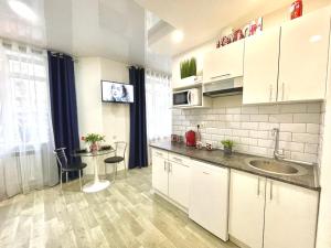 eine Küche mit einem Waschbecken und einem Tisch mit Stühlen in der Unterkunft Apartment Studio London 51 in Irpin