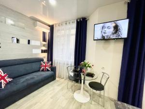 a living room with a couch and a tv on a wall at Apartment Studio London 51 in Irpin