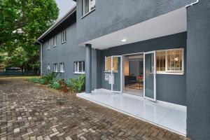 uma casa cinzenta com um pátio em frente em Inn & Out Sandton em Joanesburgo