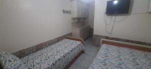 a small room with two beds and a tv at Atalay Pansiyon in Harbiye
