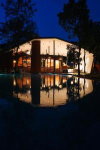 a building with a reflection in a pool of water at night at Vyna Hillock Resort and Spa in Vythiri