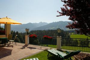 a patio with chairs and an umbrella and mountains at Hotel Martin in Ramsau am Dachstein