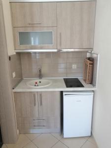 a small kitchen with a sink and a refrigerator at Sunny summer time in Nea Vrasna