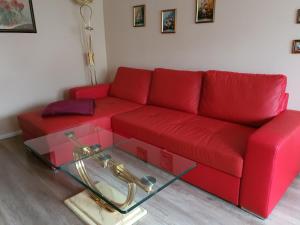 1 sofá rojo con mesa de cristal en la sala de estar en Ferienwohnung an der Dresdner Heide - Langebrück, en Dresden